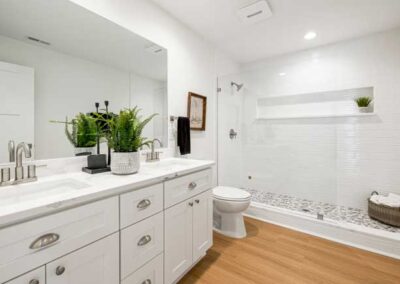 A pristine bathroom with white cabinets and a shower.